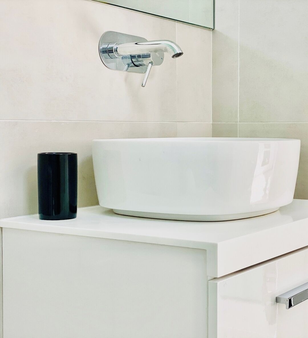 Une salle de bain avec un lavabo blanc, une tasse noire et un robinet chromé.