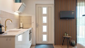 Une cuisine moderne équipée d’un four encastré, d’un évier et d’un téléviseur à écran plat fixé au mur.