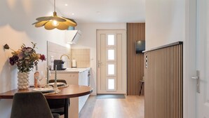 Une cuisine moderne avec un coin repas, un plancher en bois et un vase décoratif rempli de fleurs.