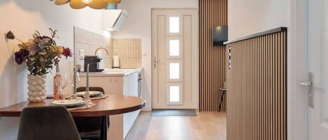 Una cocina moderna con comedor, suelo de madera y un jarrón decorativo con flores.