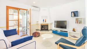 Una sala de estar moderna con un sofá, sillones, un televisor, una chimenea y una estantería.