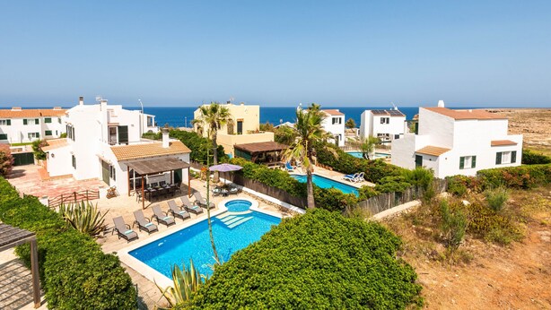 Un resort con piscina, sillas de descanso y vista al mar.