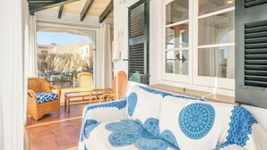 Una habitación acogedora con sofá y sillas de mimbre, ventanas amplias con contraventanas y vistas al exterior.
