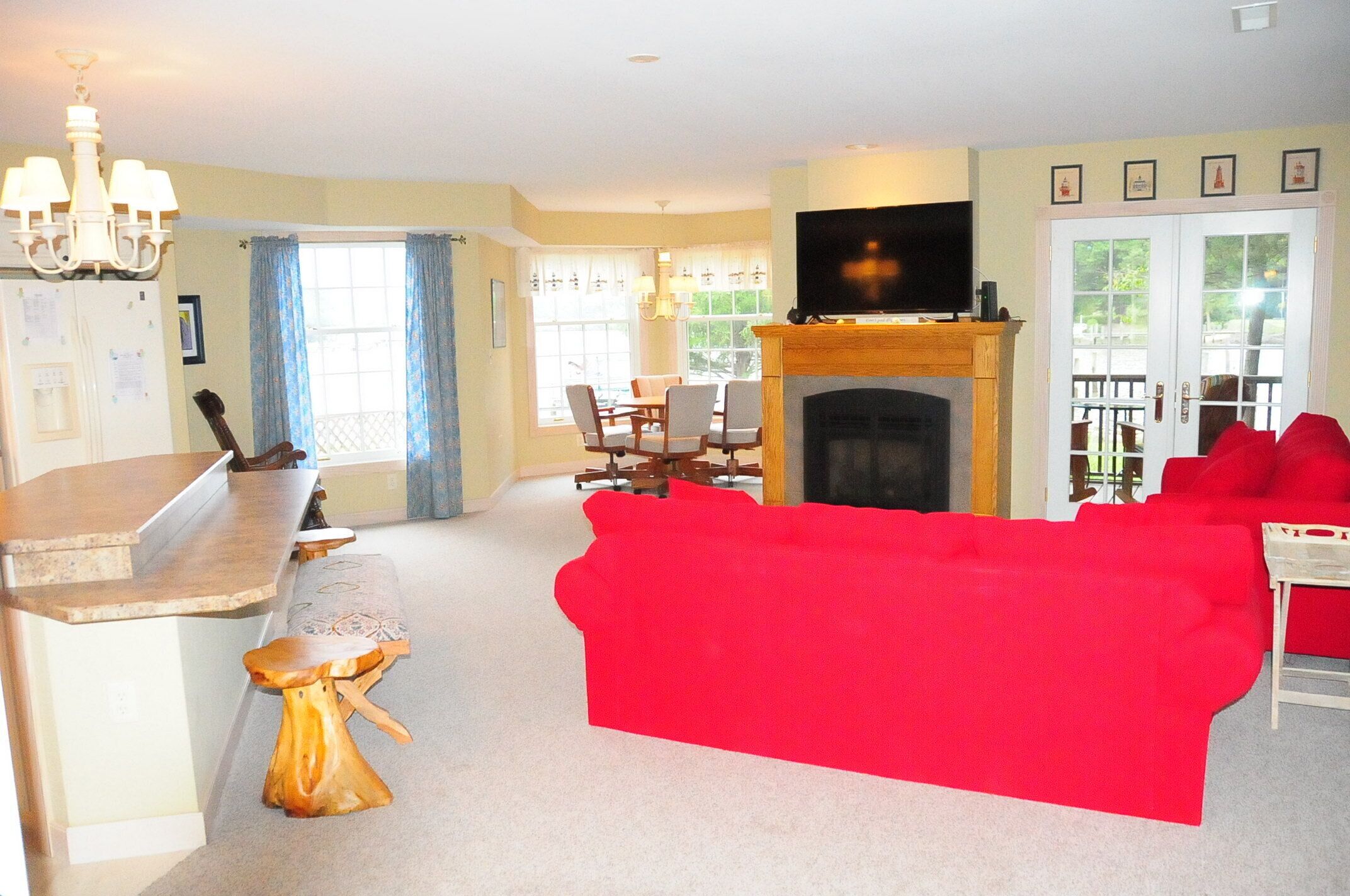 A living room with a red sofa, a fireplace, a television, and a dining area with chairs and a table.
