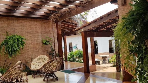 An outdoor patio with brick walls, wooden pergola, and wicker chairs. - Hotel do Porto (Porto Franco)