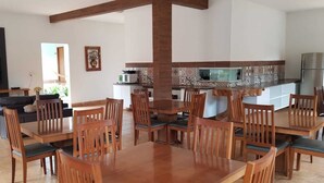 A spacious living area with a large wooden dining table and chairs, a sofa, a flat-screen TV, and a kitchen area with a refrigerator and microwave. - Hotel do Porto (Porto Franco)