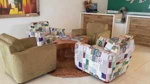 A living room with a beige sofa, a patterned armchair, and a small wooden coffee table. - Hotel do Porto (Porto Franco)