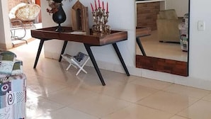 A modern living room with a tiled floor, a wooden coffee table with decorative items, a large mirror, and a brick wall. - Hotel do Porto (Porto Franco)