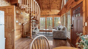A wooden cabin interior with a staircase, a sofa, and a dining area. - Time to Get Cozy! King Bed I Hot Tub I Foosball Table I Cabin for Couples (Sevierville)
