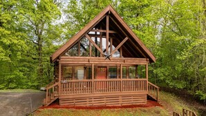 A wooden cabin with a balcony, surrounded by trees. - Time to Get Cozy! King Bed I Hot Tub I Foosball Table I Cabin for Couples (Sevierville)
