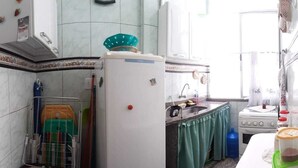A compact kitchen with a refrigerator, a sink, a stove, and a small countertop. - Apartment 170m from Praia do Forte (Centro)