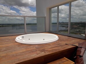 Een moderne kamer met een groot raam, een houten vloer en een witte badkuip.