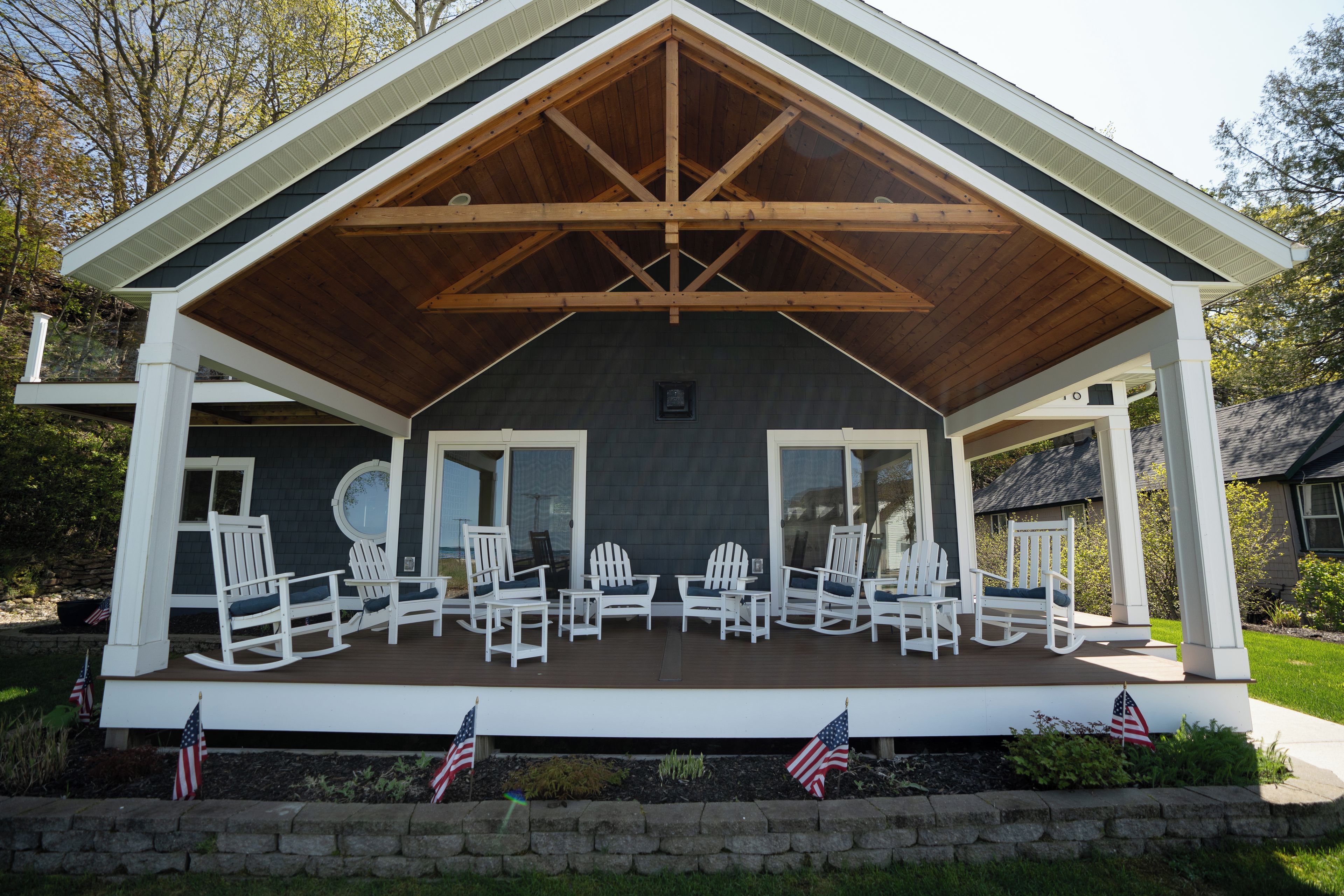 Un porche cubierto con sillas Adirondack blancas e insignias de Estados Unidos.