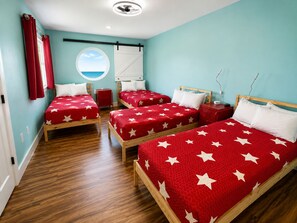 Una habitación de hotel con tres camas, cada una con un edredón rojo adornado con estrellas blancas.