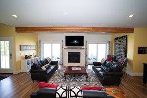 Una sala de estar con chimenea, dos sofás, una mesa de centro y un televisor sobre la chimenea.