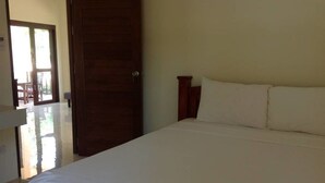 Een slaapkamer met een groot bed, een houten deur en uitzicht op een terras.