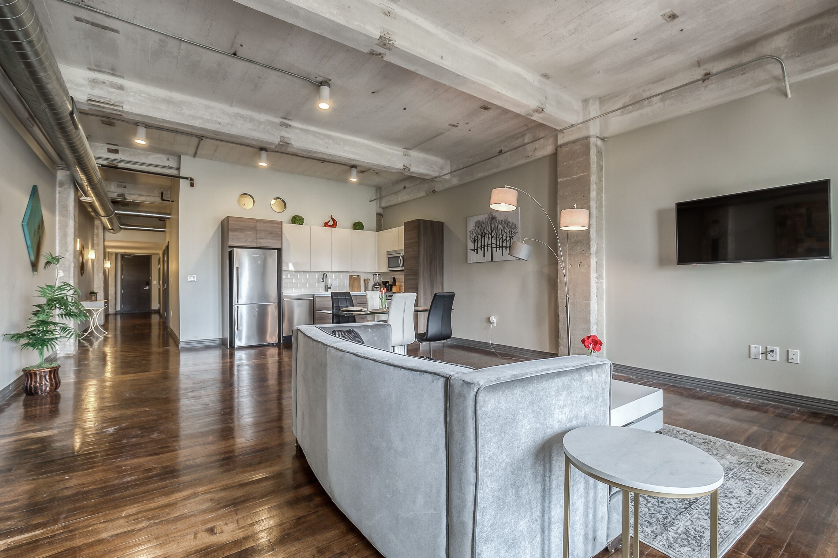 A modern kitchen with a central island, stainless steel appliances, and a flat-screen TV mounted on the wall.
