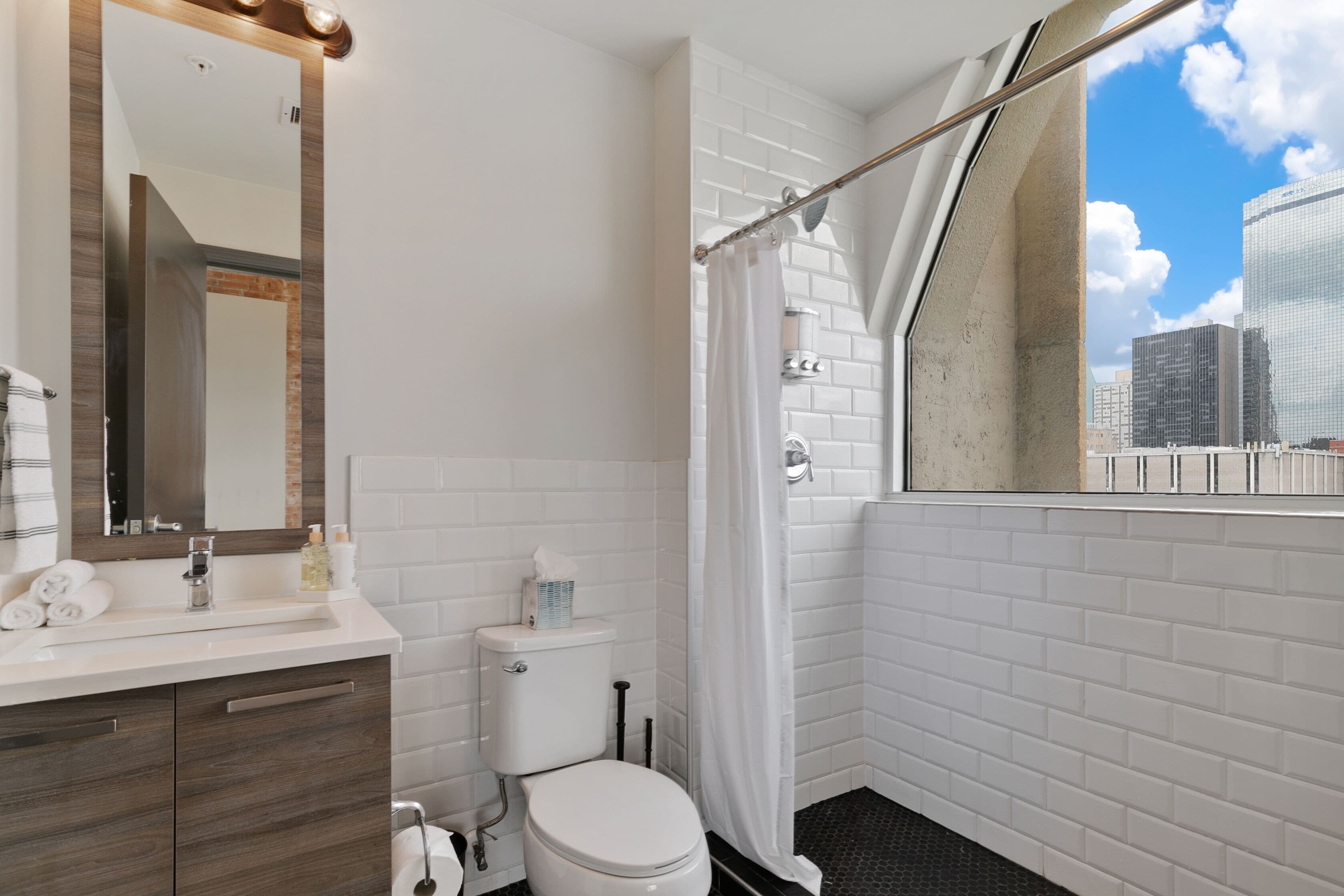 A modern bathroom with a white toilet, a sink with a mirror, and a shower area.