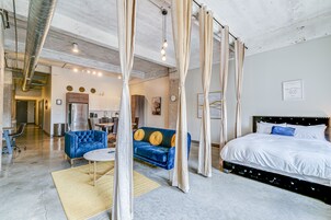 Un dormitorio moderno con una cama grande, un sofá azul y un comedor al fondo.