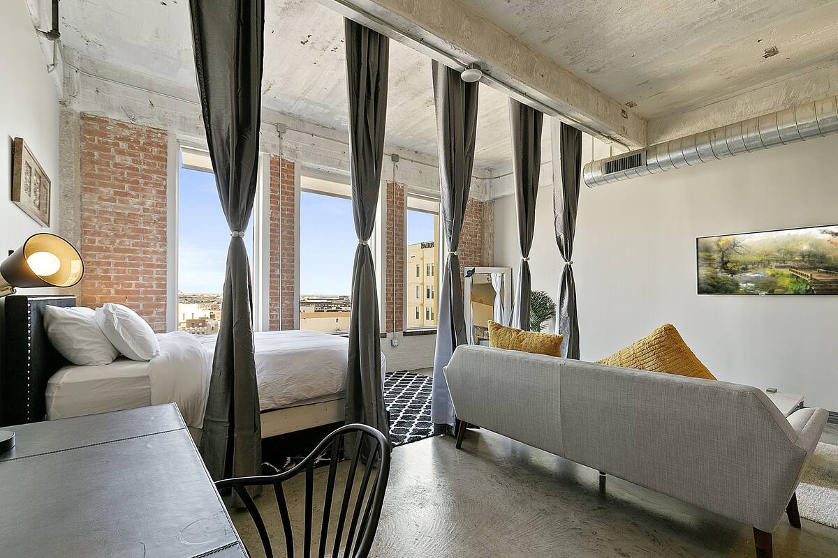 Hotellihuone, jossa on sänky, sohva, työpöytä ja tuoli.