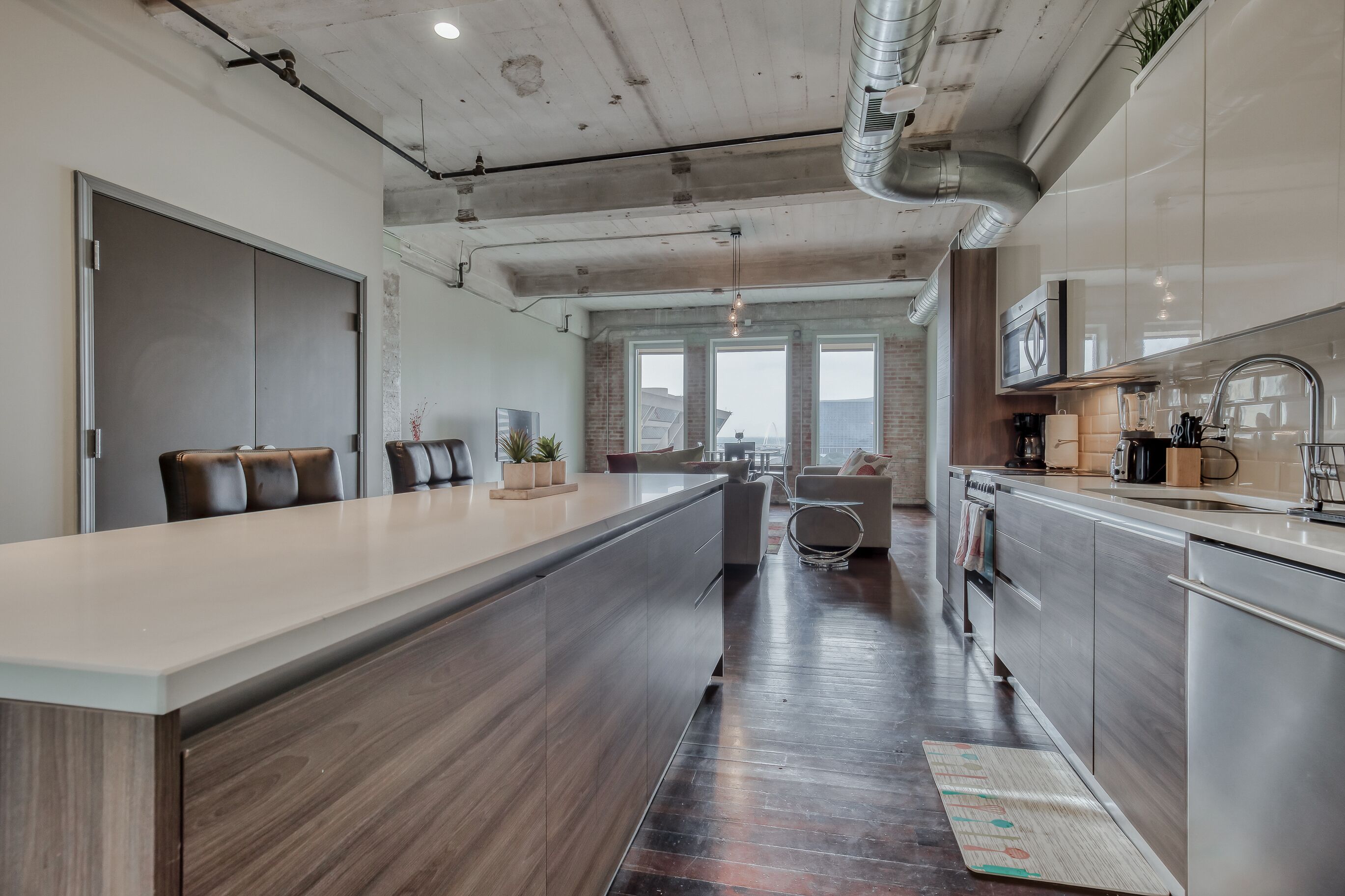 A modern kitchen with a central island, stainless steel appliances, and a view to the outside.