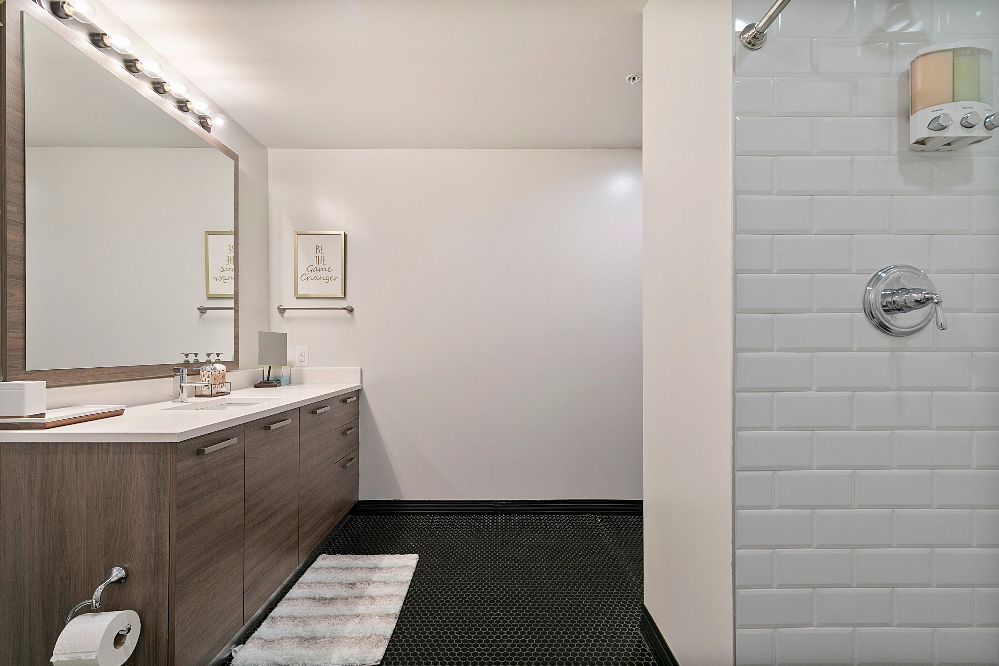 A modern bathroom with a vanity, mirror, and a shower area.