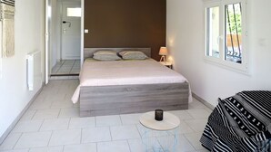 Un dormitorio con cama, mesita de noche, lámpara y vistas por la ventana.