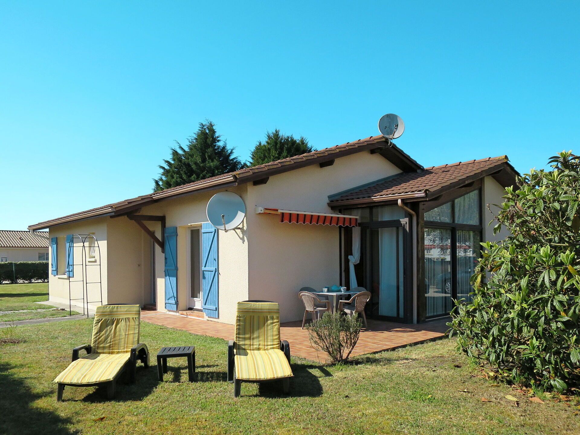 Una casa con un patio, dos sillones, una mesa y una antena parabólica.