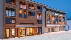 Un hotel moderno con varios pisos, ventanas amplias y un restaurante.