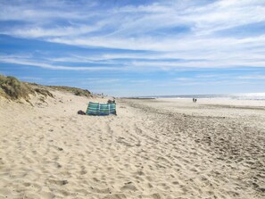 En strand med ett randigt strandparasoll och ett tält.
