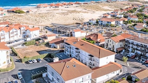 A coastal residential area with multiple buildings, a beach, and a clear view of the ocean.
