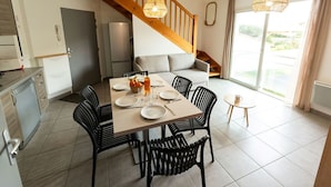 A modern kitchen with a dishwasher, a refrigerator, and a dining area with a table set for four.