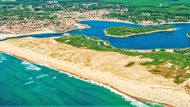 Ein Luftbild einer Küstenstadt mit Strand, einer Bucht und einer kleinen Insel.