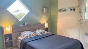 Quarto com cama, mesas de cabeceira, janela e decorações nas paredes.