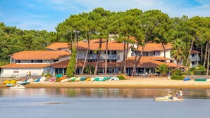 Un hotel sulla costa con numerosi balconi, una spiaggia sabbiosa e diverse imbarcazioni colorate.