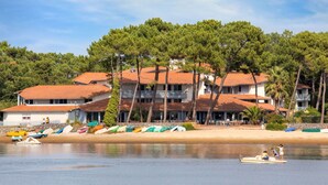 Un edificio costiero con numerosi balconi, una spiaggia sabbiosa e diverse imbarcazioni colorate.