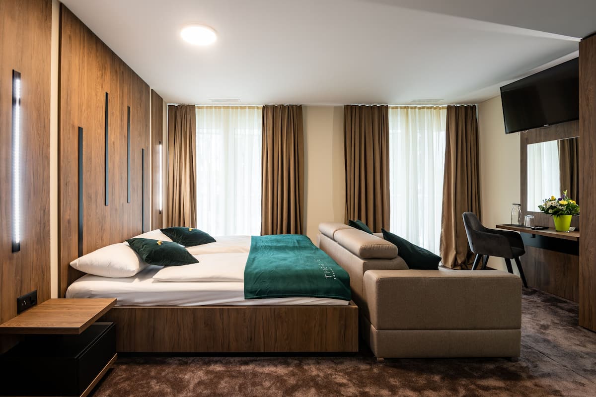 Une chambre d’hôtel moderne équipée d’un lit, d’un canapé, d’un bureau et d’une télévision.