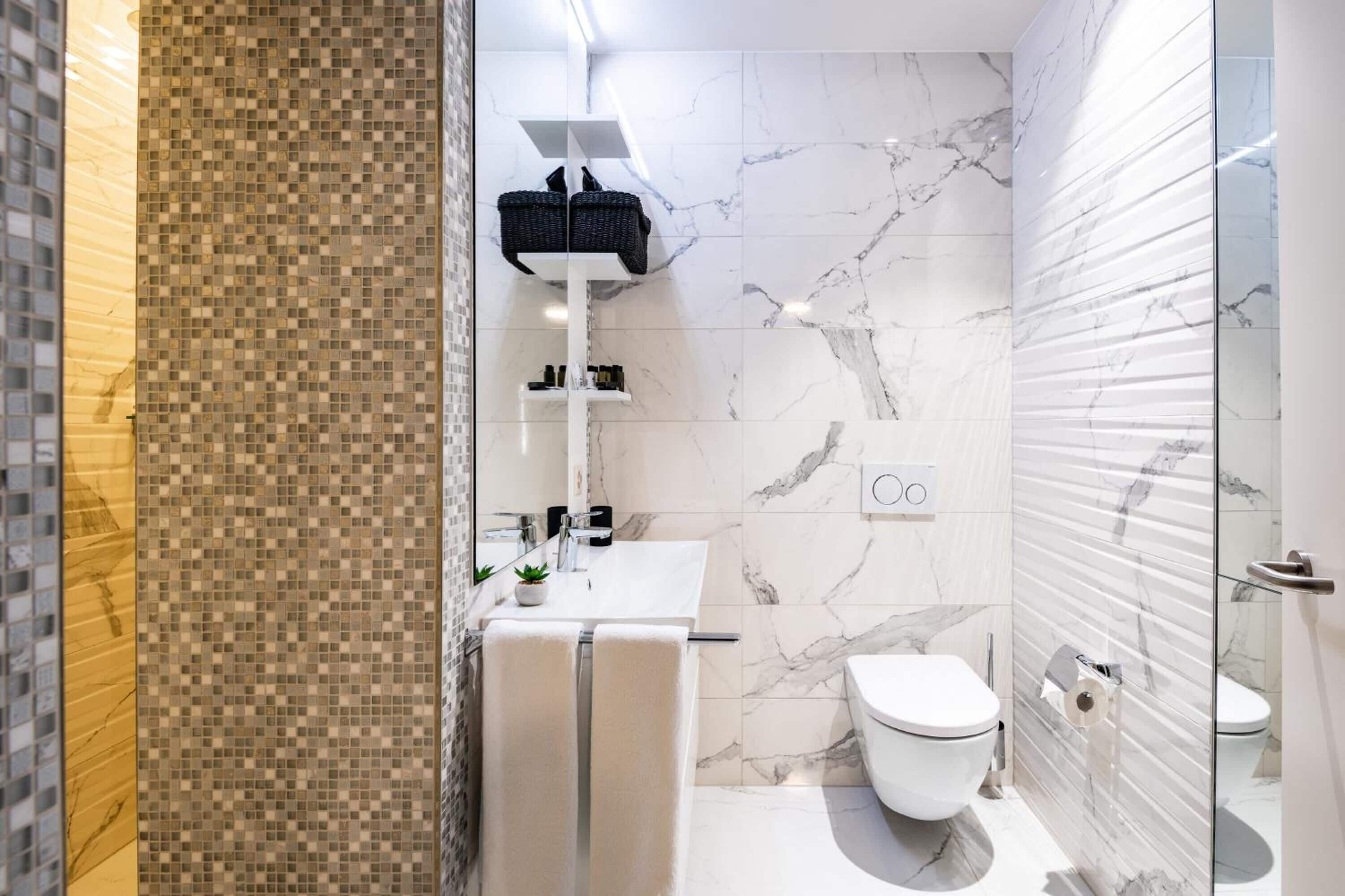 A modern bathroom with a white sink, a toilet, and a glass shower enclosure.