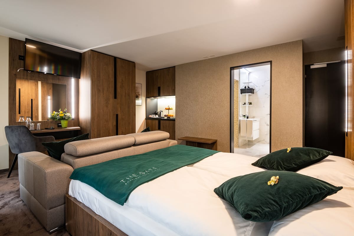 Une chambre d’hôtel moderne, équipée d’un lit, d’un bureau, d’une chaise et d’une salle de bain visible à travers une porte ouverte.