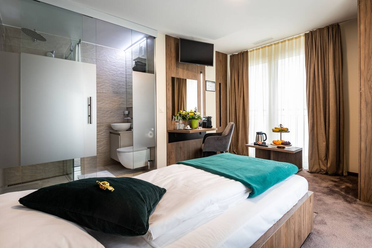 Une chambre d’hôtel moderne équipée d’un lit, d’un bureau, d’une douche et d’une télévision.