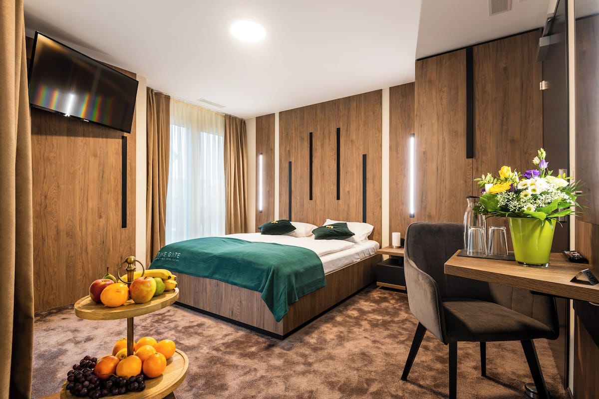 Une chambre d’hôtel moderne équipée d’un lit, d’un bureau et d’une corbeille de fruits.