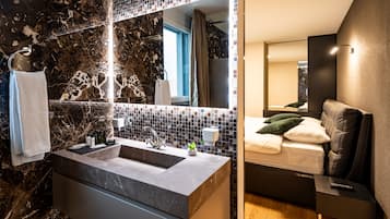 A modern bathroom with a marble sink, a large mirror, and a shower area.