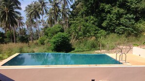 A rectangular swimming pool with a tiled edge, surrounded by a grassy area and palm trees. - Ban Sabai 2 - Koh Phangan (Koh Phangan)