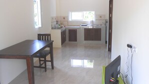 A kitchen with a dining table and chairs, a window, and a computer on a desk. - Ban Sabai 2 - Koh Phangan (Koh Phangan)