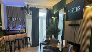 A modern living room with a grey sofa, a dining area with a bar, and a TV mounted on the wall. - McGraths Blackpool (Blackpool)