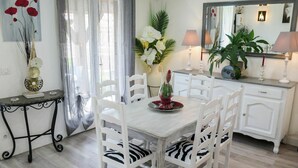 A dining area with a white table and chairs, a vase with flowers, a mirror, and a lamp on a cabinet. - Wonderful private villa for 4 guests with private pool, WIFI, TV, terrace and pets allowed (Labenne)