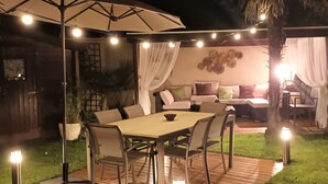An outdoor patio with a wooden table and chairs, surrounded by a pergola with string lights. - Wonderful private villa for 4 guests with private pool, WIFI, TV, terrace and pets allowed (Labenne)