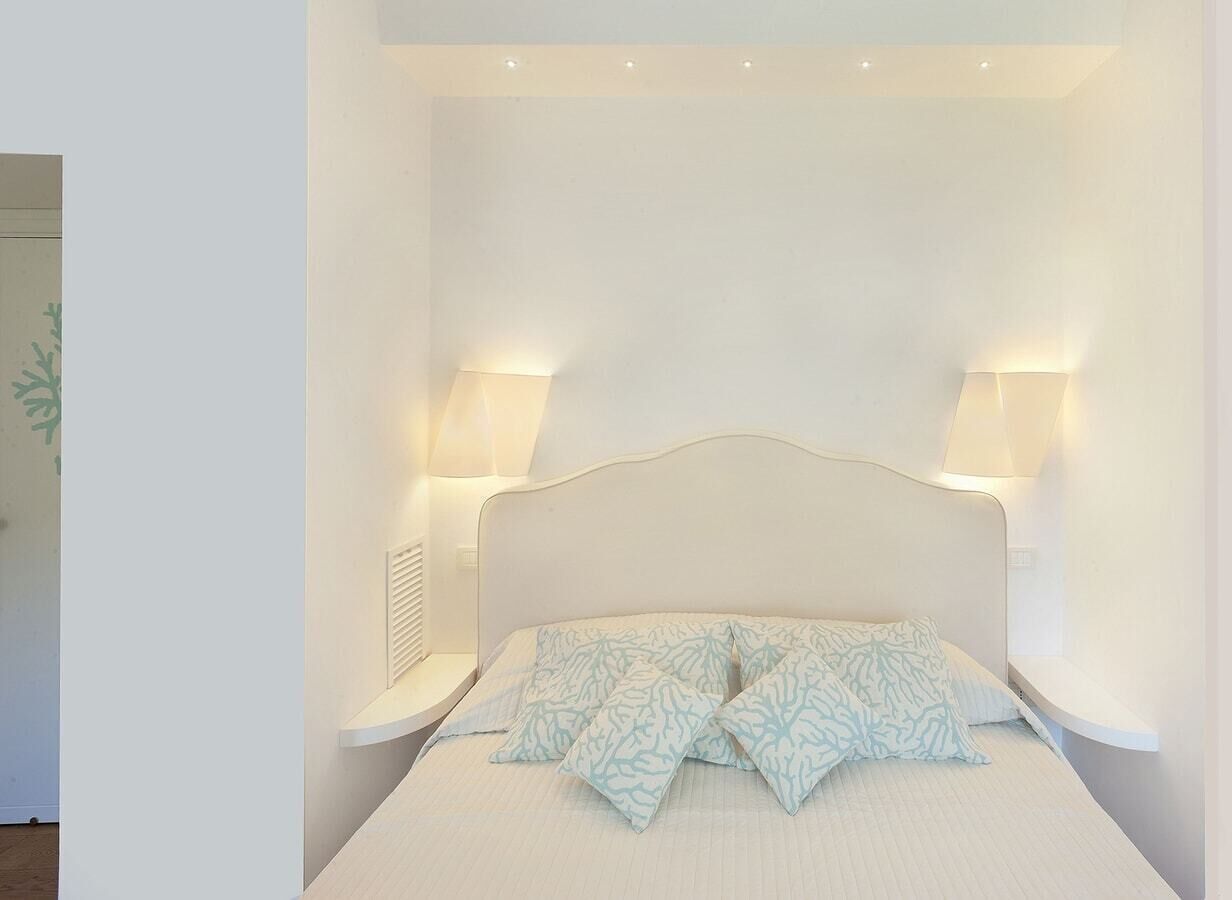 A neatly arranged bedroom with a bed, two bedside lamps, and a nightstand.