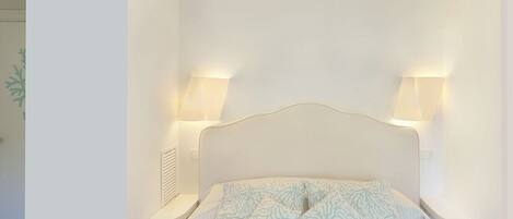 A neatly arranged bedroom with a bed, two bedside lamps, and a nightstand.