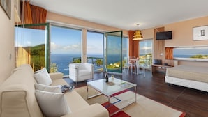 Ein modernes Hotelzimmer mit großem Balkon, einer Couch, einem Couchtisch und einem Fernseher.